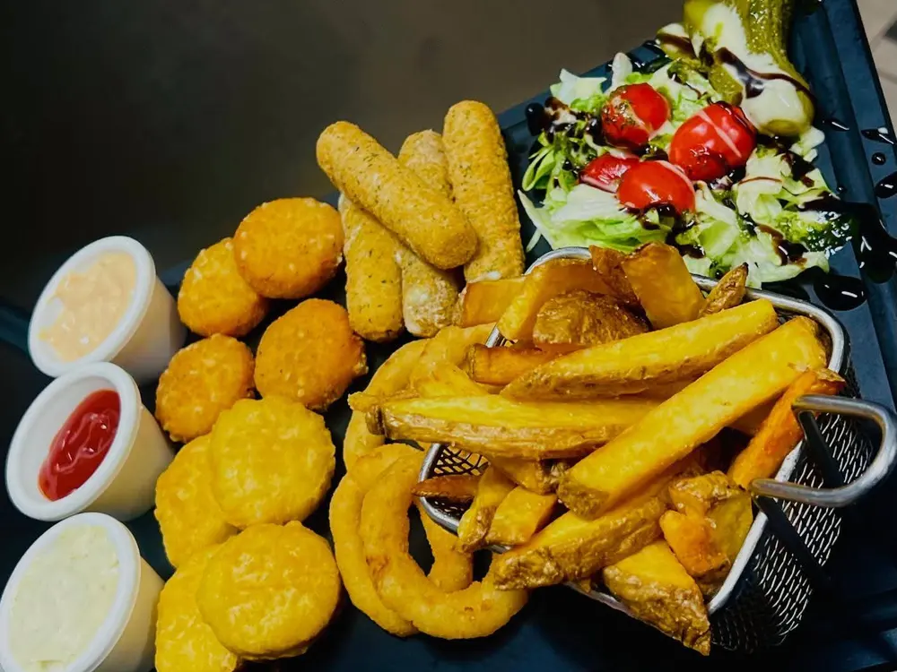 Assortiment de finger food : nuggets, sticks de mozzarella, onion rings, frites, salade et sauces